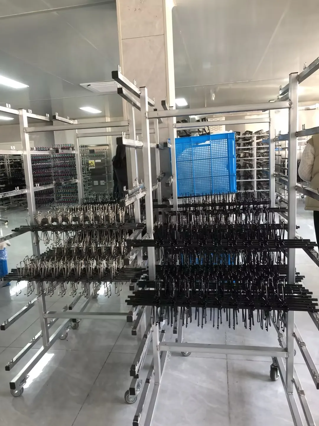 Metal eyewear frames and temples resting on hanging racks between finishing stages at the Three Hippos factory