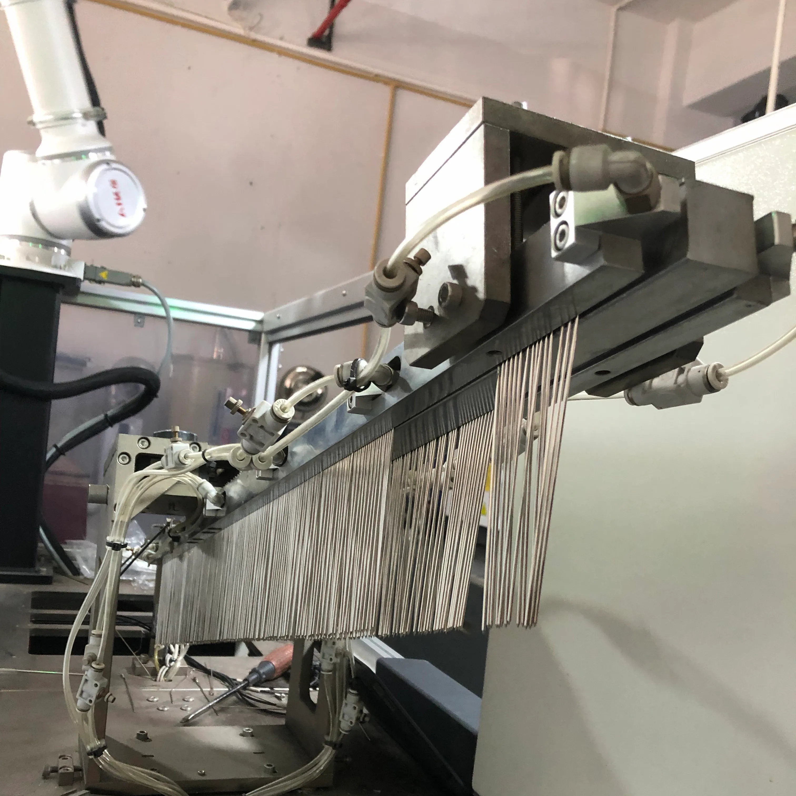 Automated pin-insertion machine feeding metal hinge pins for eyewear temples at the Three Hippos factory
